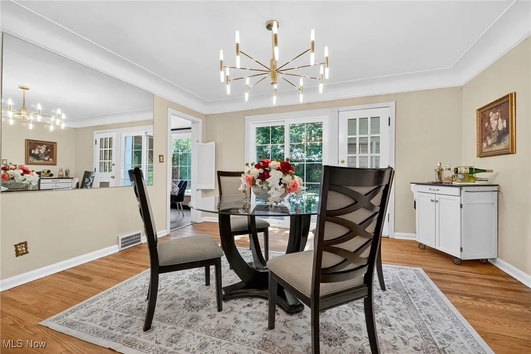 Dining space featuring a chandelier, light wood-type flooring, french doors, and crown molding
