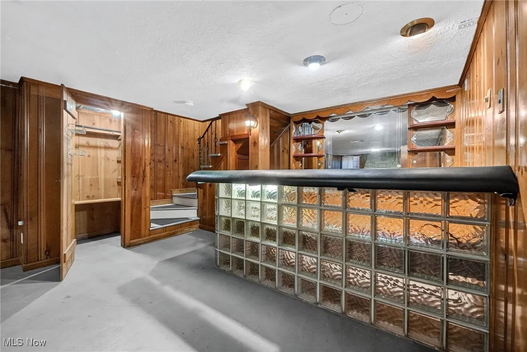 Welcome area with wood walls, stairway, a dry bar, and a textured ceiling