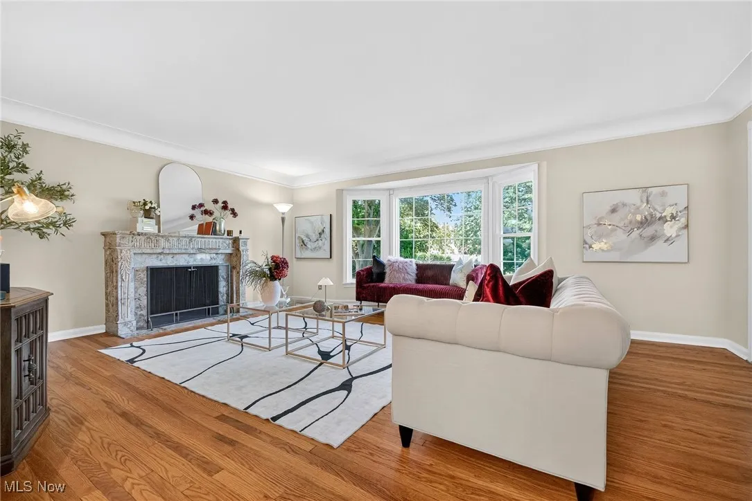 Living room with a premium fireplace, crown molding, and wood finished floors