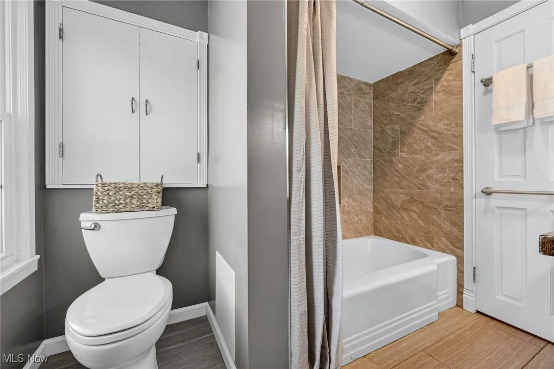 Bathroom featuring shower / tub combo and wood finished floors