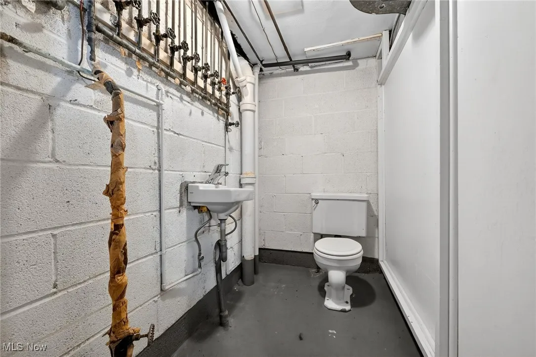 Half bath featuring concrete floors and concrete block wall