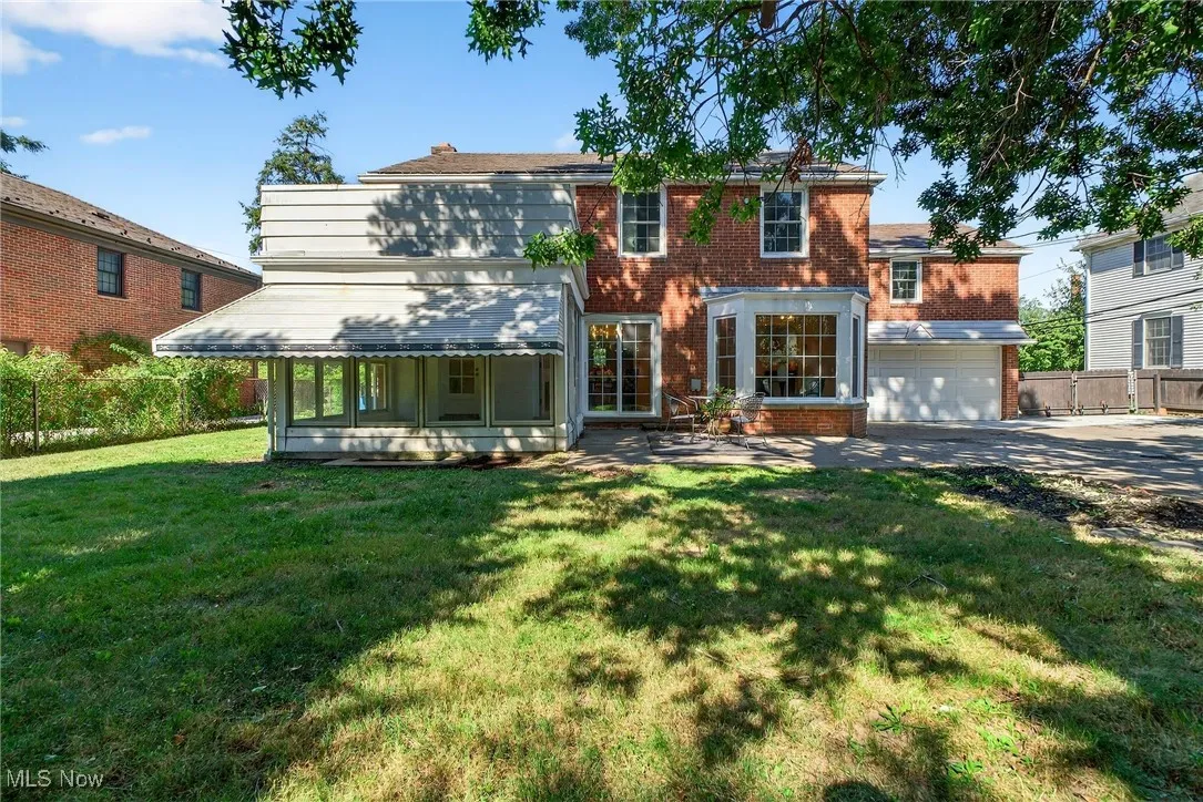 View of front of house with brick siding, concrete driveway, a patio, and an attached garage