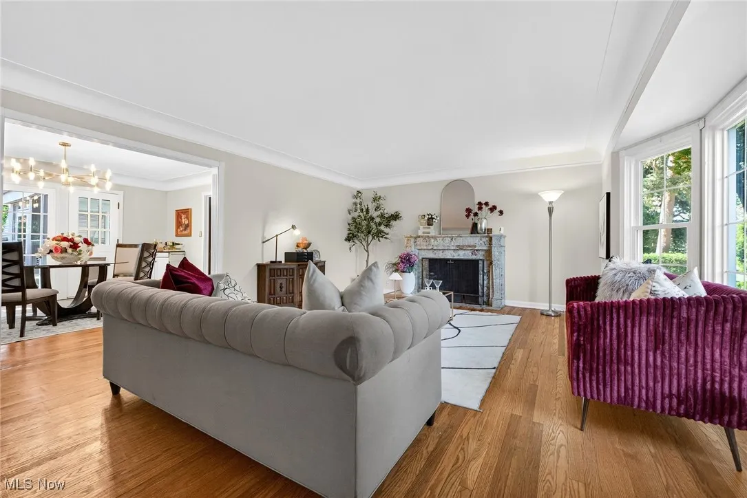Living room featuring hardwood / wood-style flooring, a premium fireplace, a chandelier, and crown molding