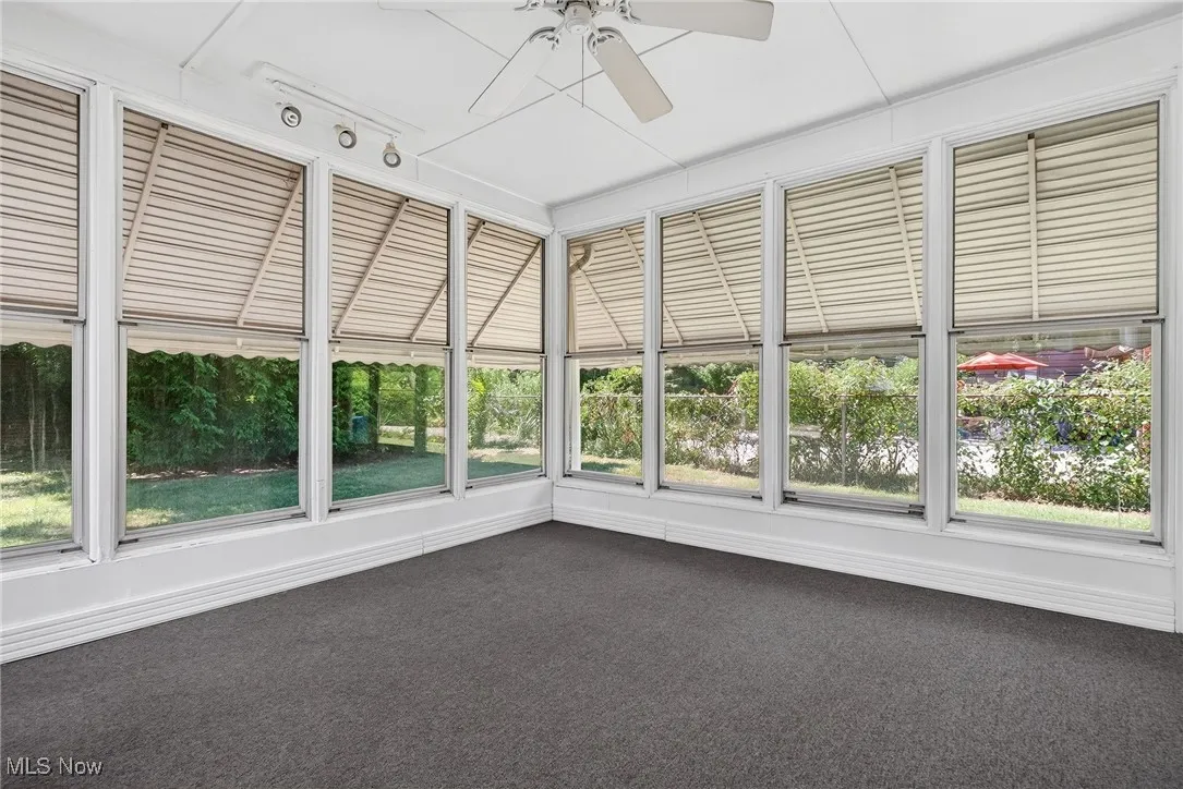 Unfurnished sunroom with carpet flooring and plenty of natural light