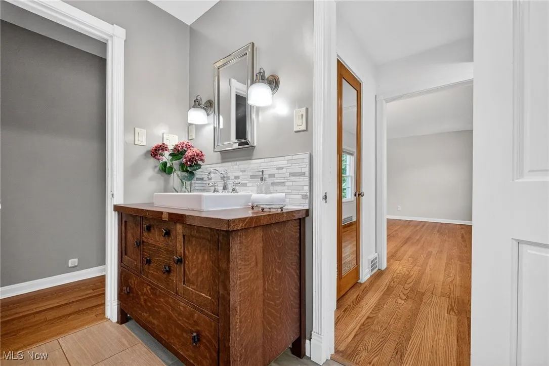 Bathroom featuring vanity, decorative backsplash, and light wood-style floors