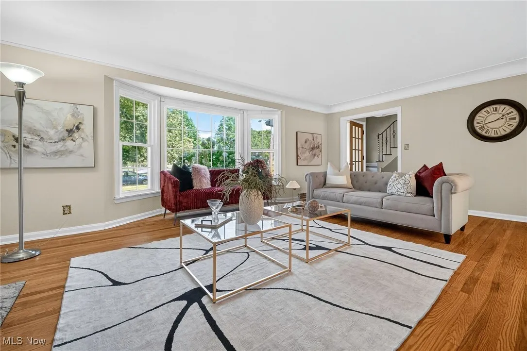 Living room with light wood-type flooring, stairs, and ornamental molding