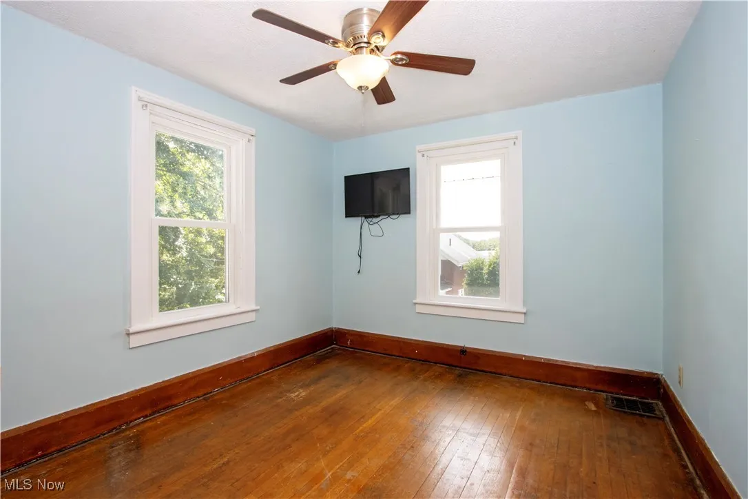 Empty room featuring hardwood / wood-style flooring and ceiling fan