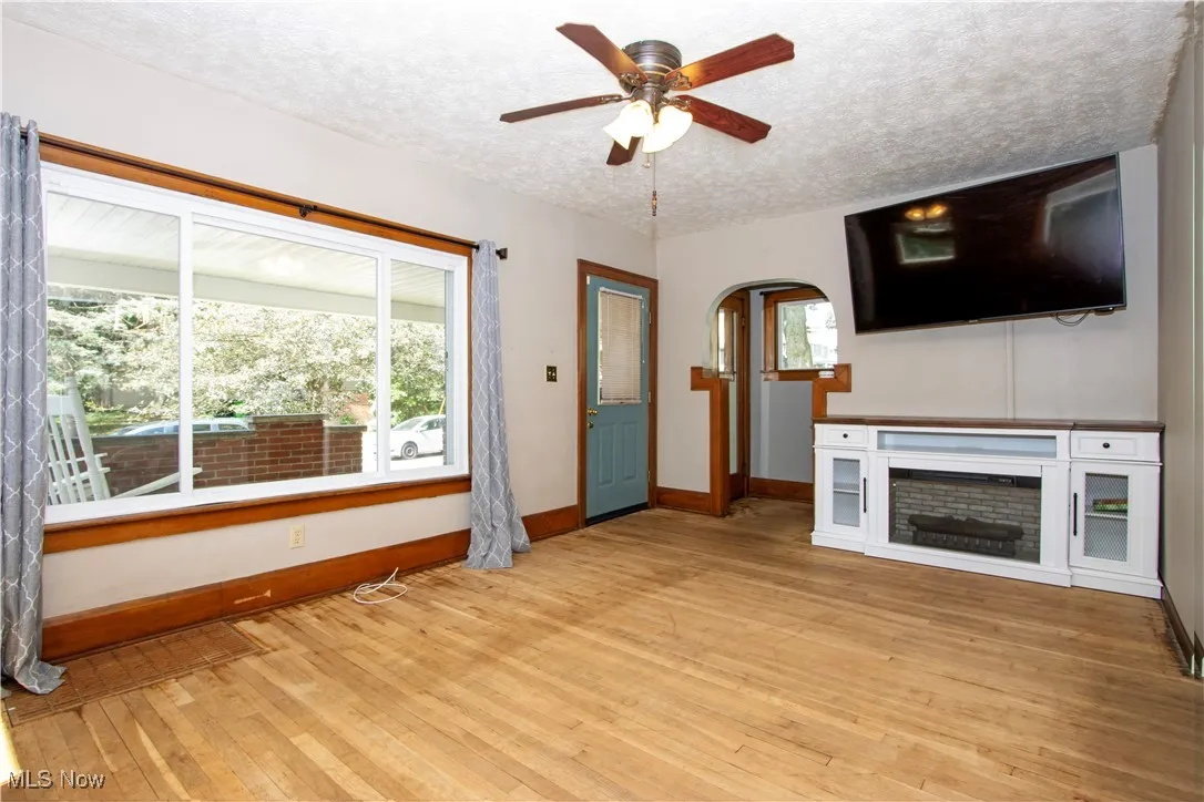 Unfurnished living room featuring a textured ceiling, plenty of natural light, light wood-type flooring, and arched walkways