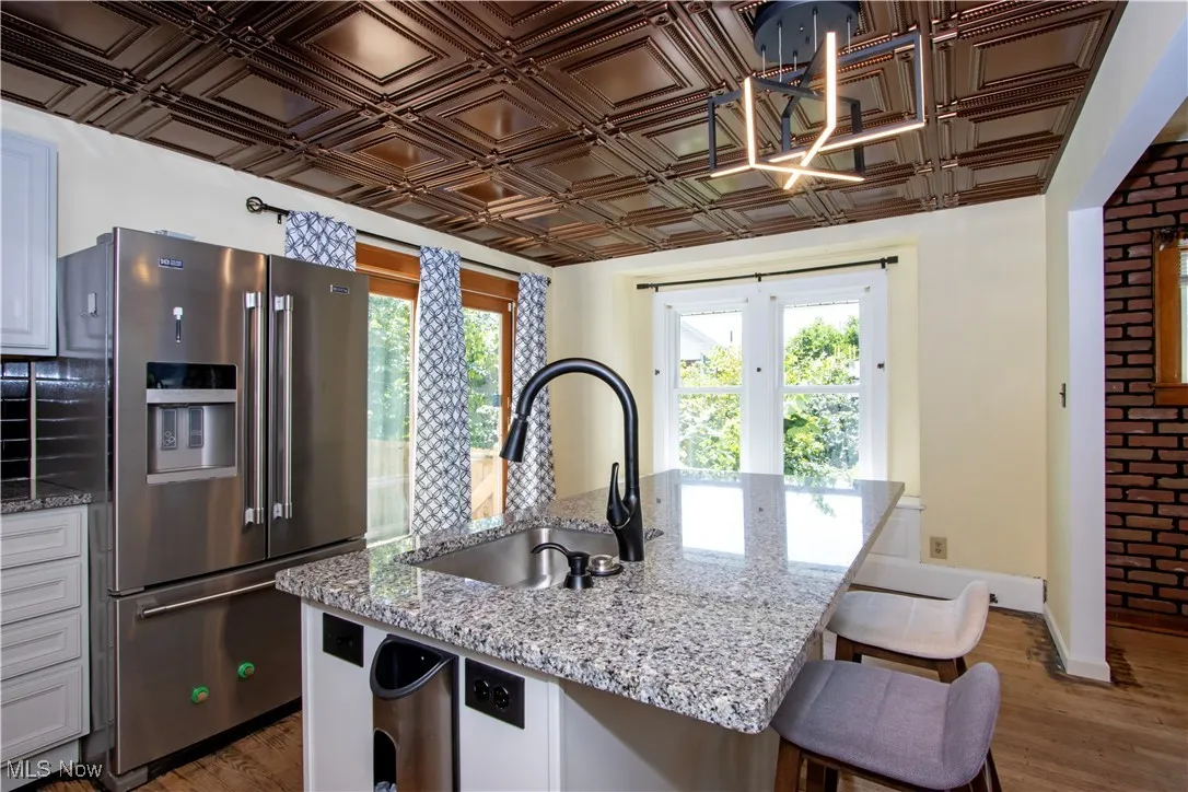 Kitchen with light stone counters, stainless steel refrigerator with ice dispenser, dark wood finished floors, and plenty of natural light