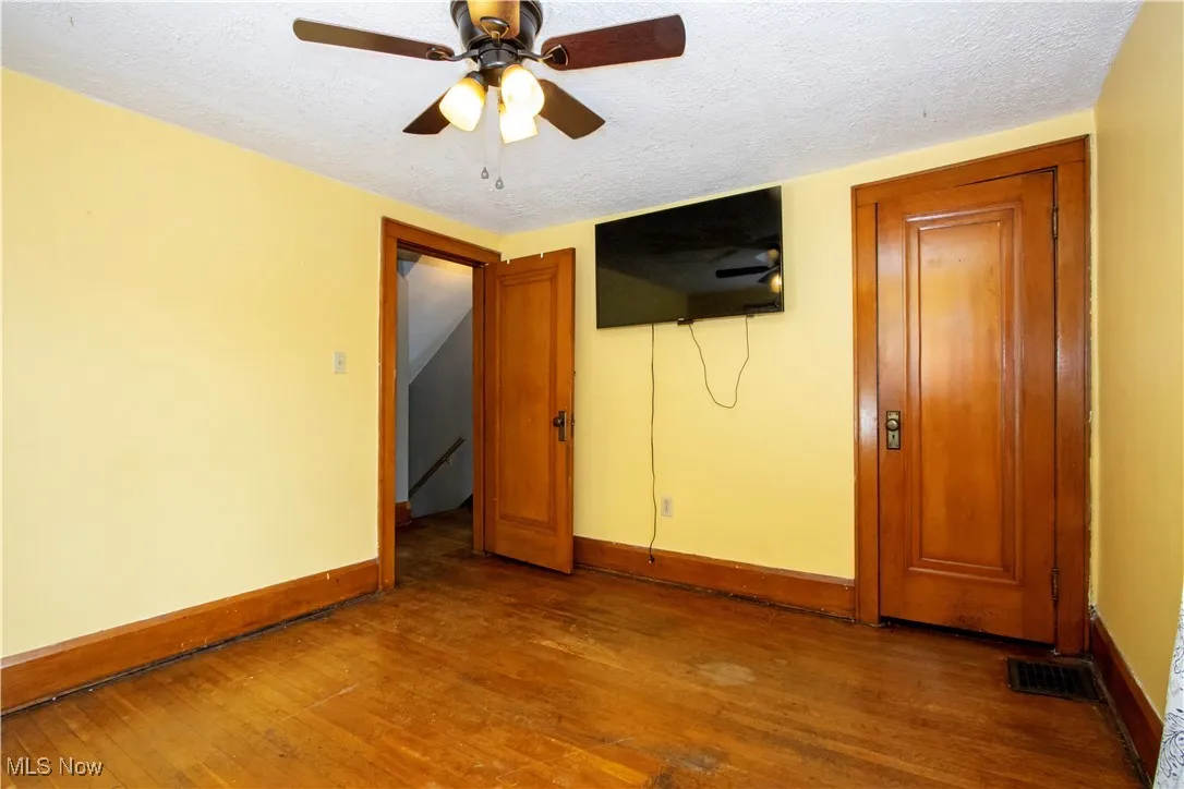 Unfurnished bedroom featuring a textured ceiling, dark wood finished floors, and ceiling fan