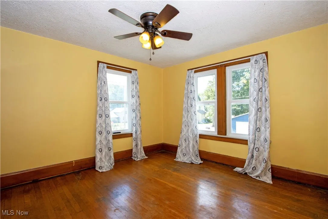 Unfurnished room featuring wood-type flooring, a textured ceiling, and ceiling fan