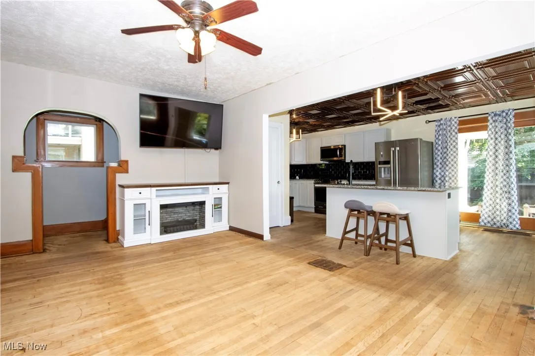 Living area with light wood-style flooring, ceiling fan, and an ornate ceiling