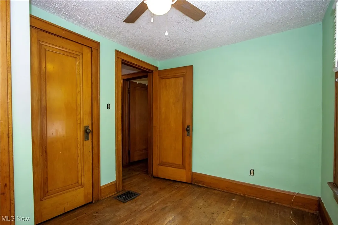 Unfurnished bedroom featuring dark wood-style flooring, a textured ceiling, ceiling fan, and a closet