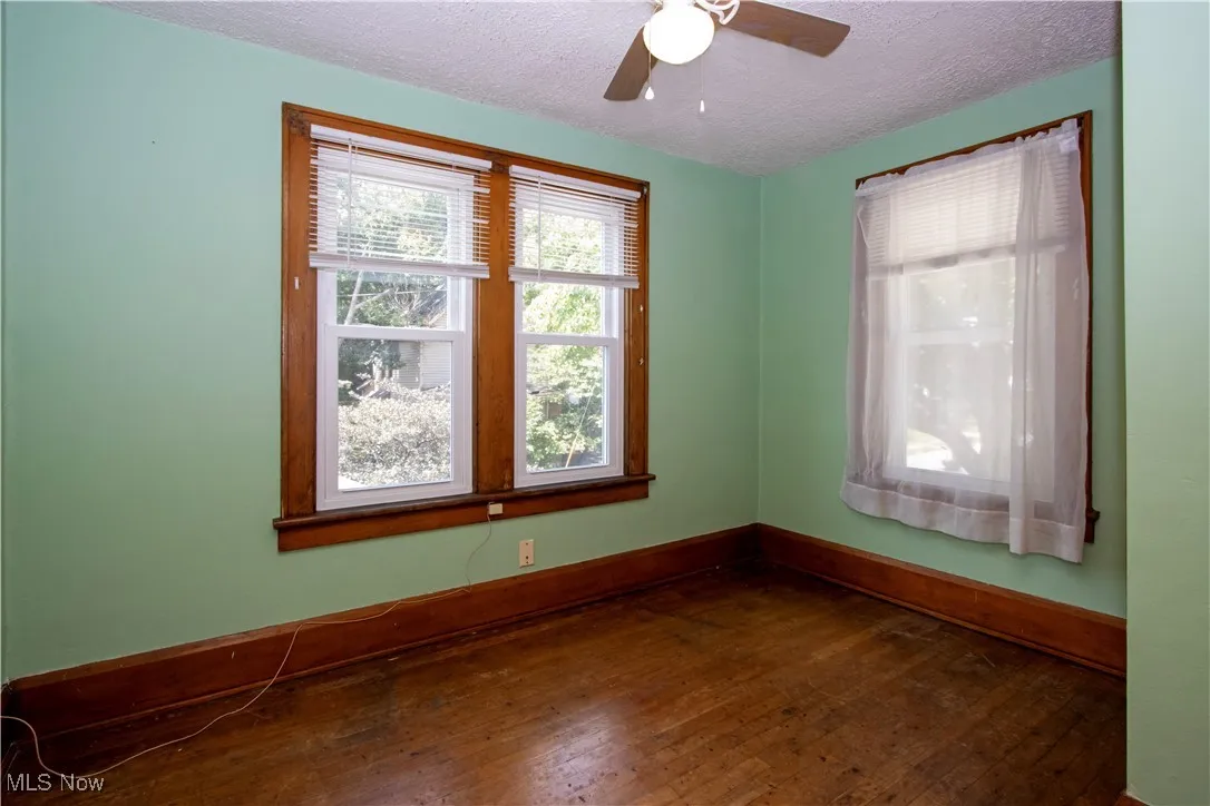 Empty room featuring dark wood finished floors, a textured ceiling, and ceiling fan