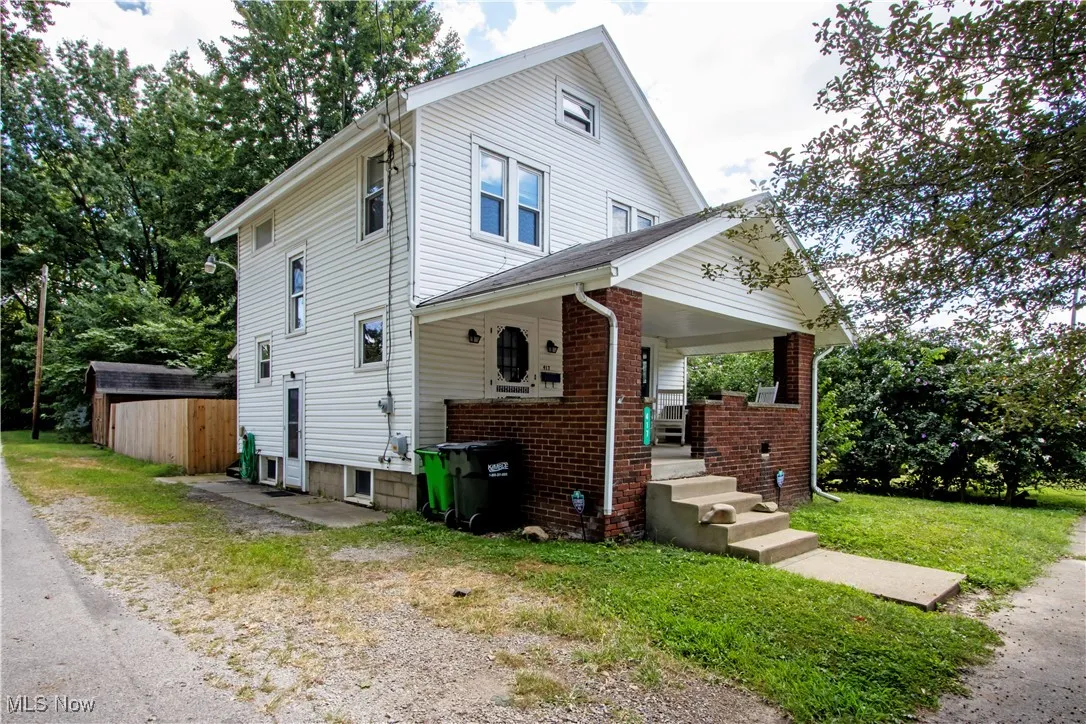 View of front facade with a porch, brick siding, and a front lawn