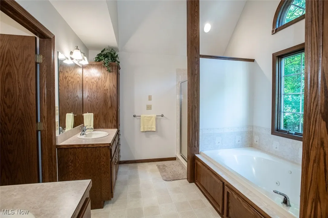 Owners suite adjoining bathroom with a jetted tub, shower, natural light, dual sink and vanities lots of storage.