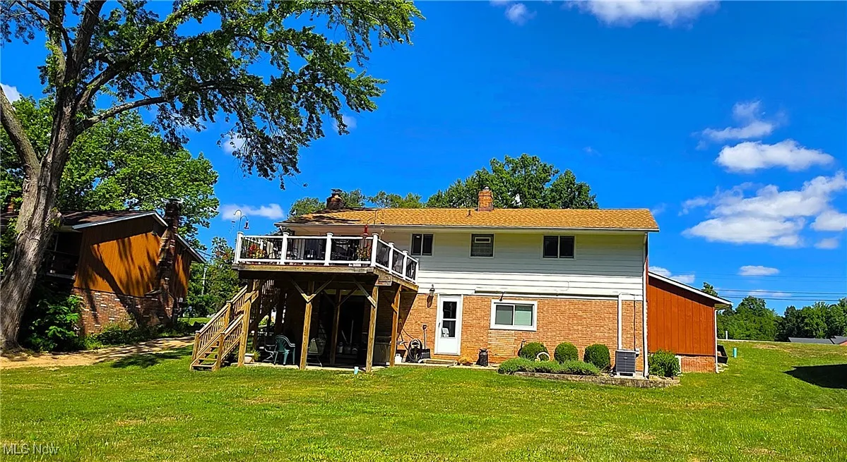 Back of property with a patio, brick siding, and a deck.
