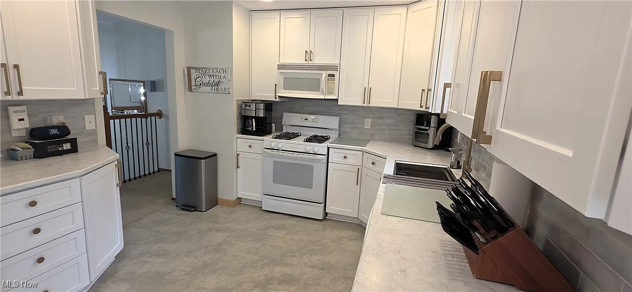 Kitchen featuring white cabinets, white appliances, and backsplash