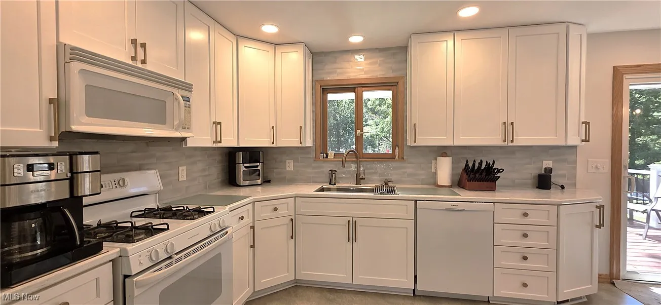 Kitchen with white appliances, white cabinets, tasteful backsplash, recessed lighting, and light stone countertops