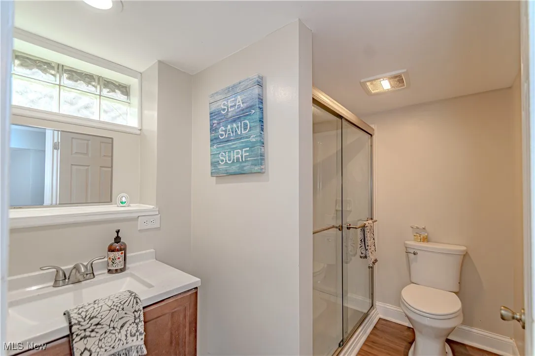 Bathroom featuring vanity, a stall shower, and wood finished floors