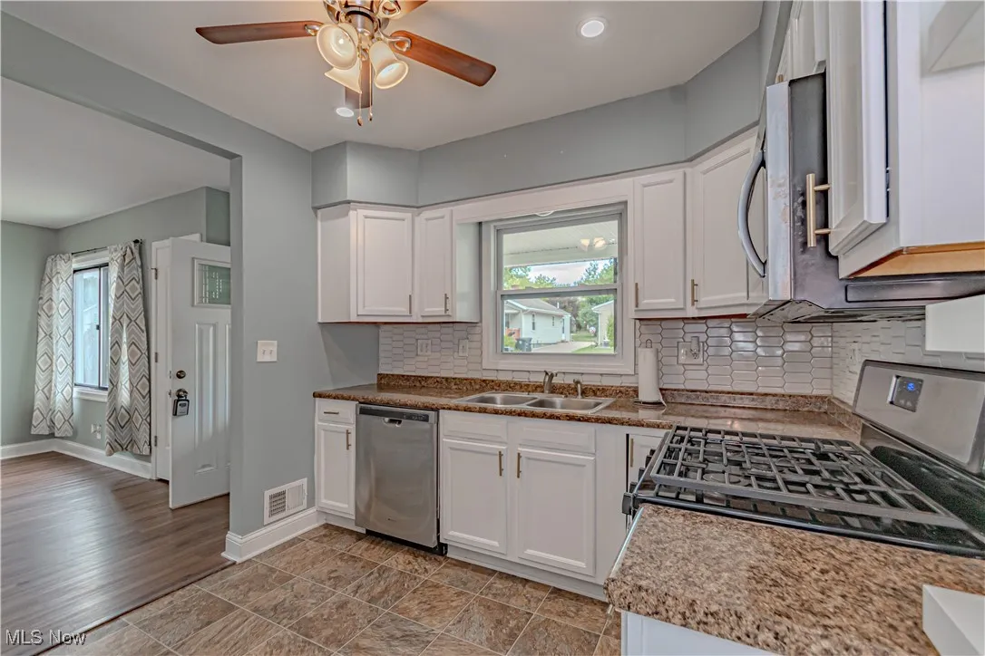 Kitchen with backsplash, appliances with stainless steel finishes, white cabinets, plenty of natural light, and recessed lighting
