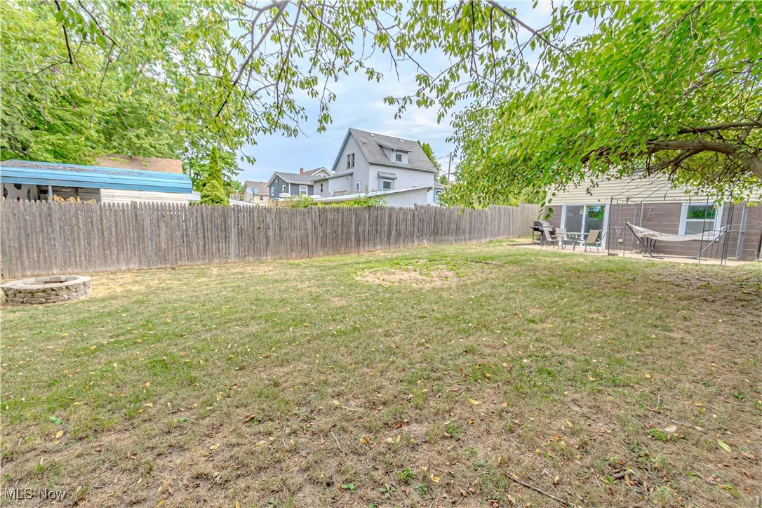 Fenced backyard with an outdoor fire pit and a patio area