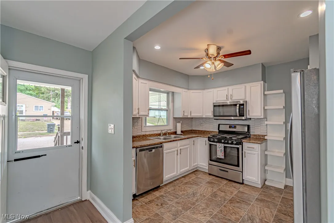Kitchen featuring stainless steel appliances, white cabinets, tasteful backsplash, dark countertops, and recessed lighting