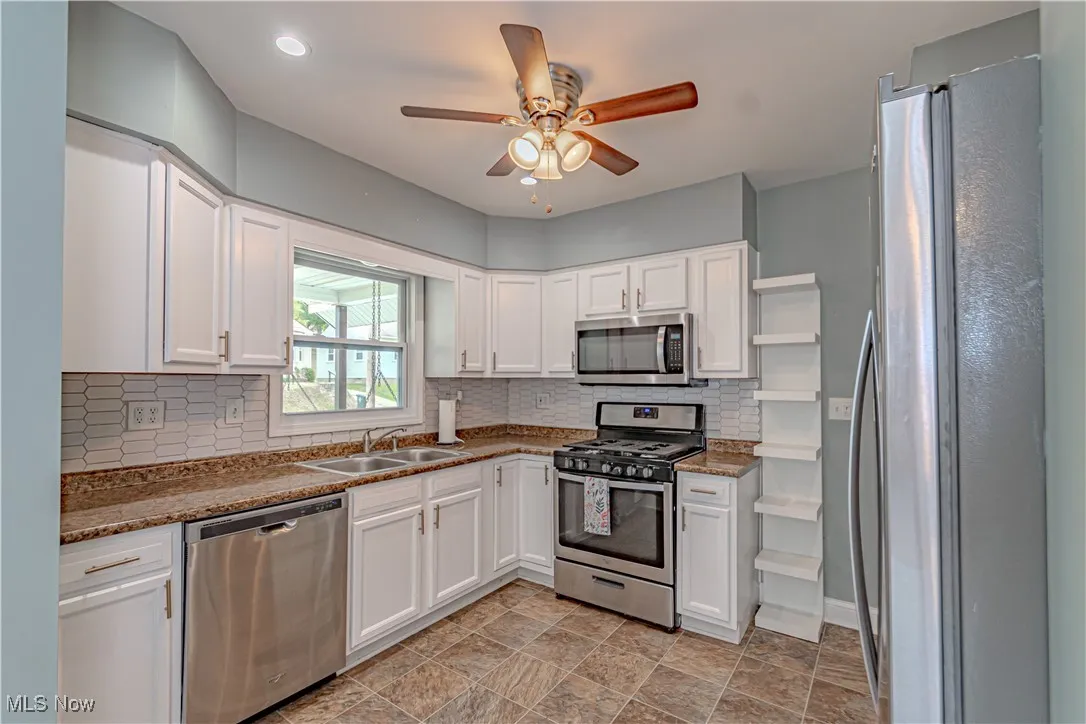 Kitchen with appliances with stainless steel finishes, white cabinetry, decorative backsplash, ceiling fan, and recessed lighting
