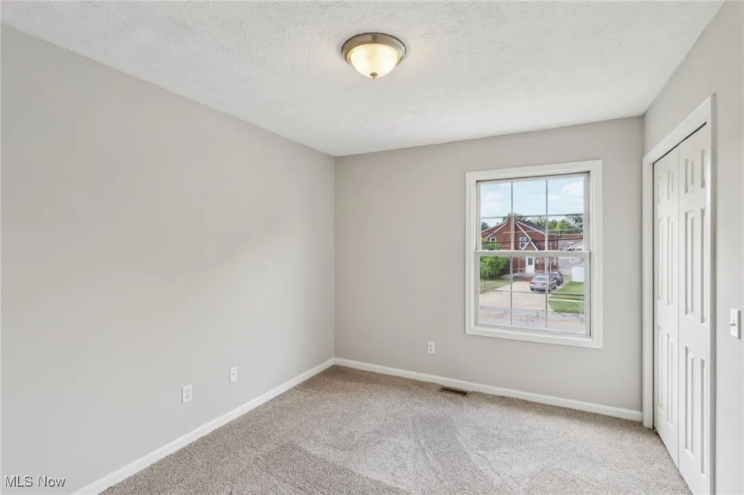 Unfurnished bedroom with light colored carpet, a closet, and a textured ceiling
