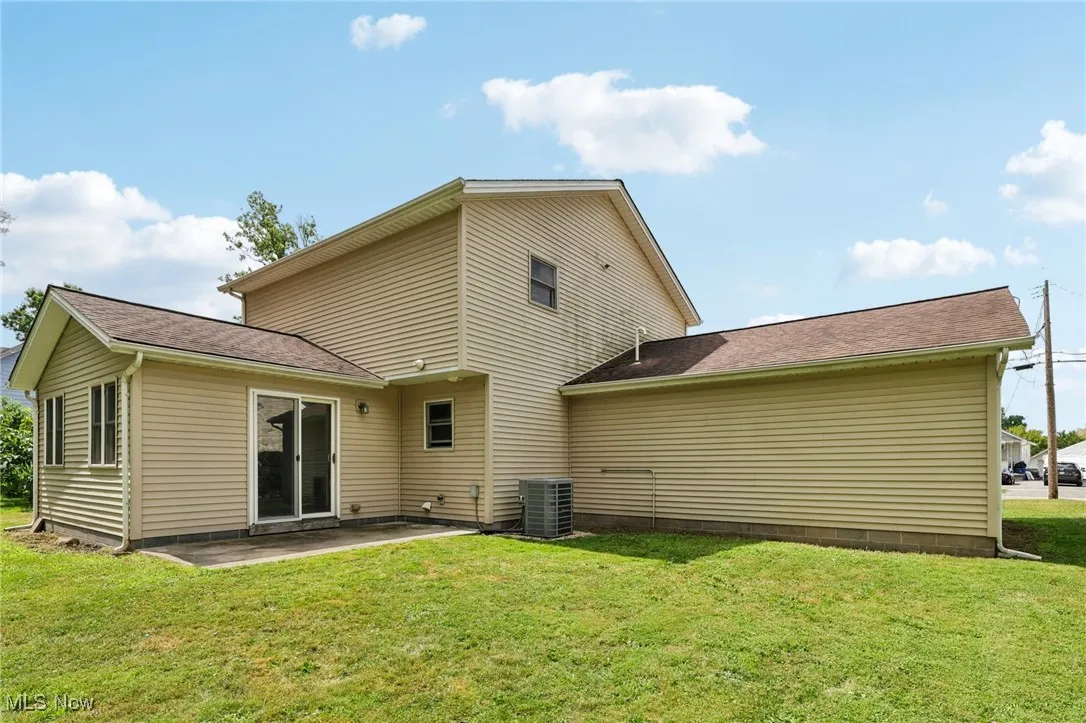 Back of house with a patio, a lawn, and a shingled roof