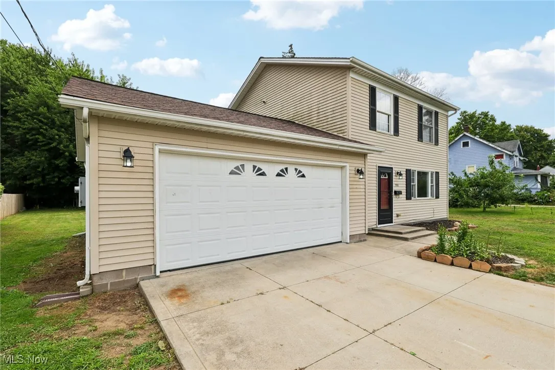 View of front of home featuring a front lawn, an attached garage, concrete driveway, and a shingled roof