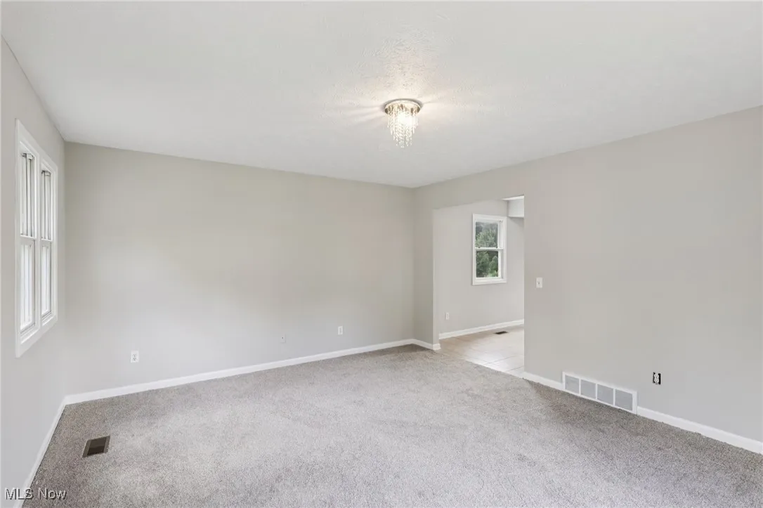 Empty room with light carpet and a textured ceiling