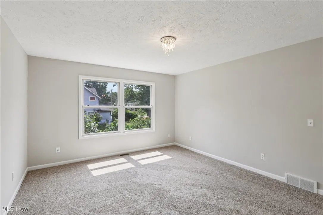 Carpeted empty room featuring a textured ceiling and baseboards
