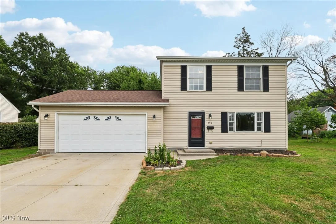 Colonial home featuring an attached garage, driveway, a front lawn, and roof with shingles