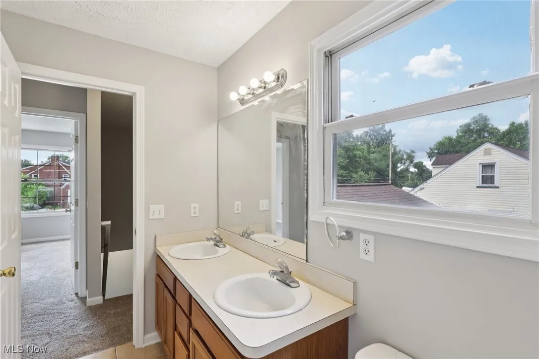 Full bath with double vanity and light tile patterned floors