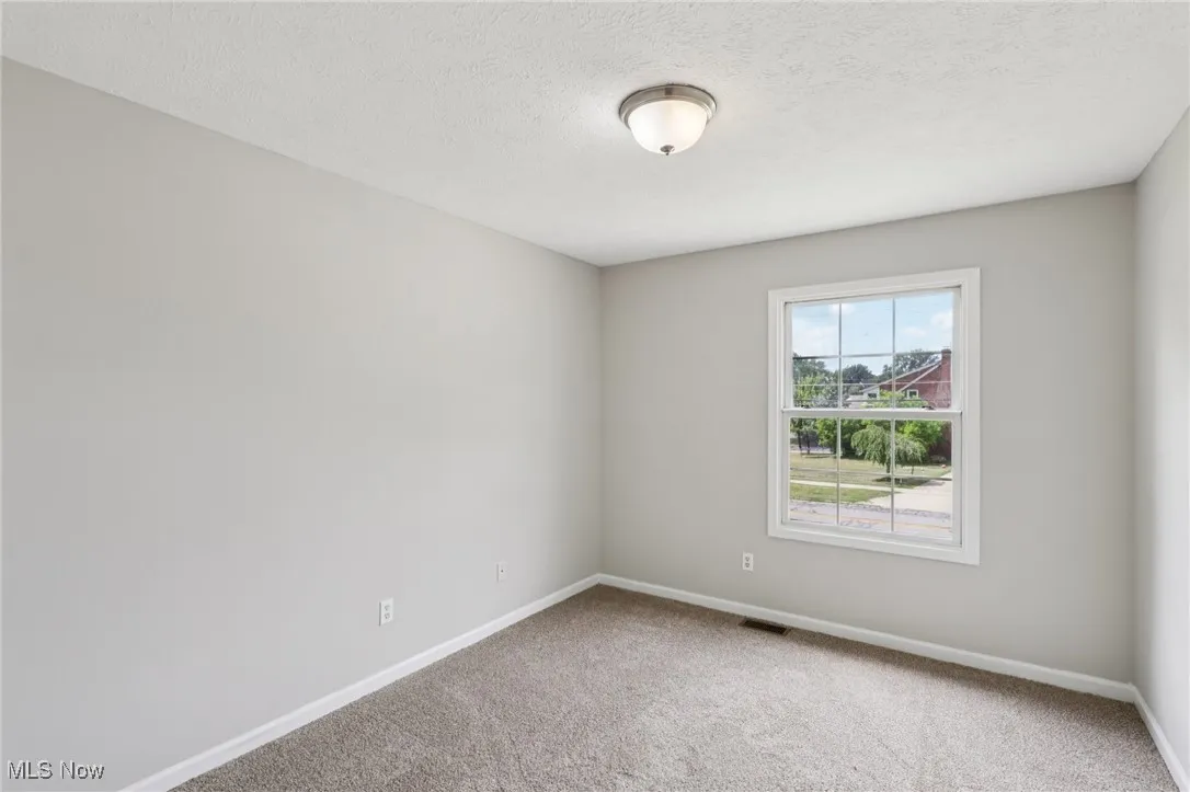 Empty room with carpet flooring and a textured ceiling