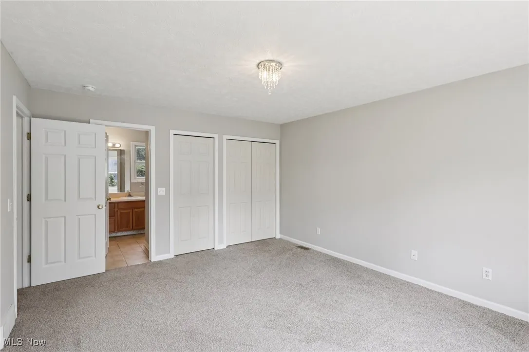 Unfurnished bedroom featuring multiple closets and light carpet