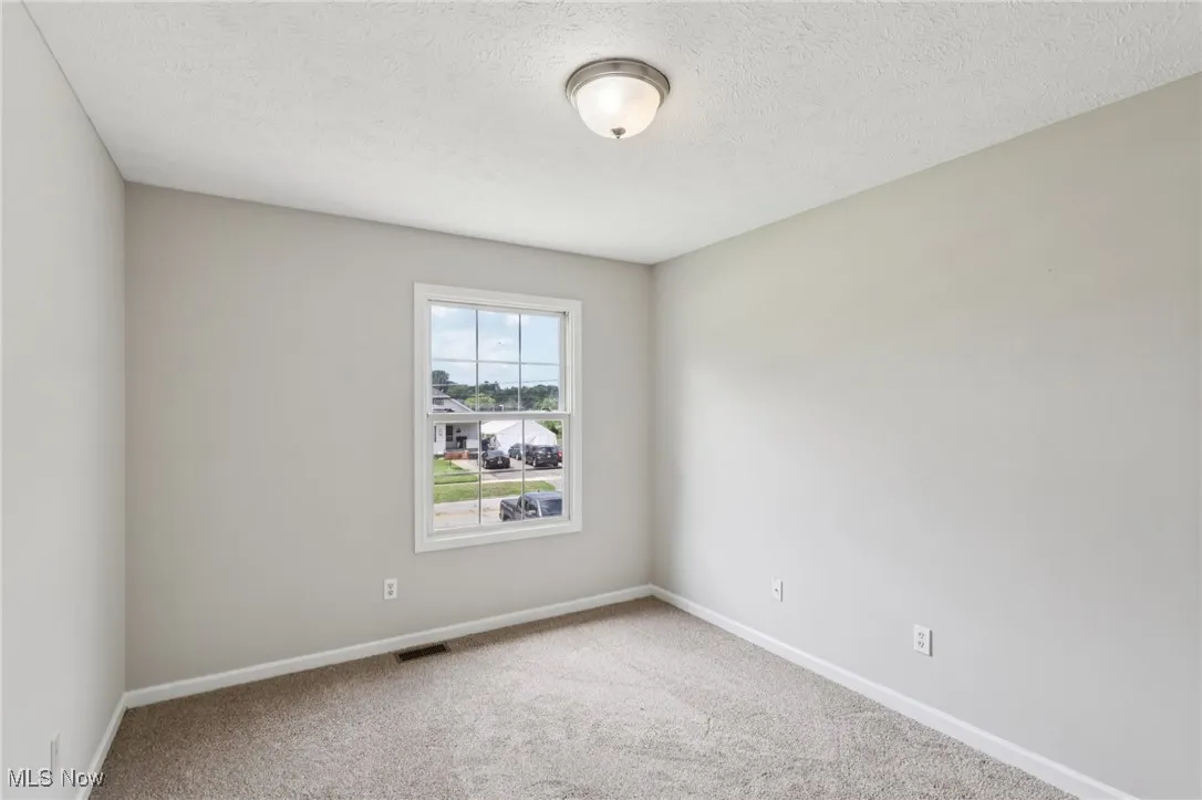 Carpeted empty room with baseboards and a textured ceiling