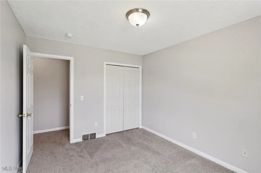 Unfurnished bedroom featuring carpet flooring, a textured ceiling, and a closet