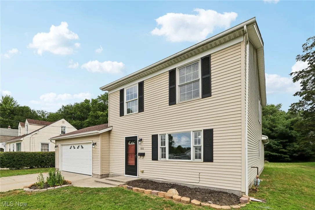 Colonial-style house with a front lawn, an attached garage, and concrete driveway