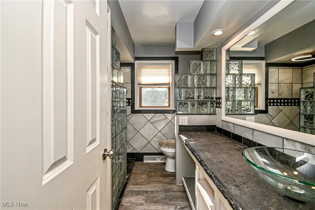 Bathroom featuring tile walls, dark wood-style floors, vanity, and recessed lighting