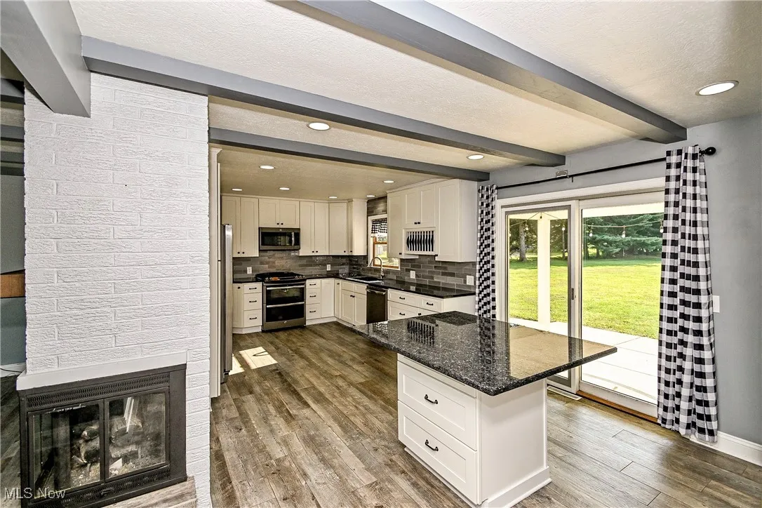Kitchen with beam ceiling, dark stone countertops, tasteful backsplash, appliances with stainless steel finishes, and recessed lighting