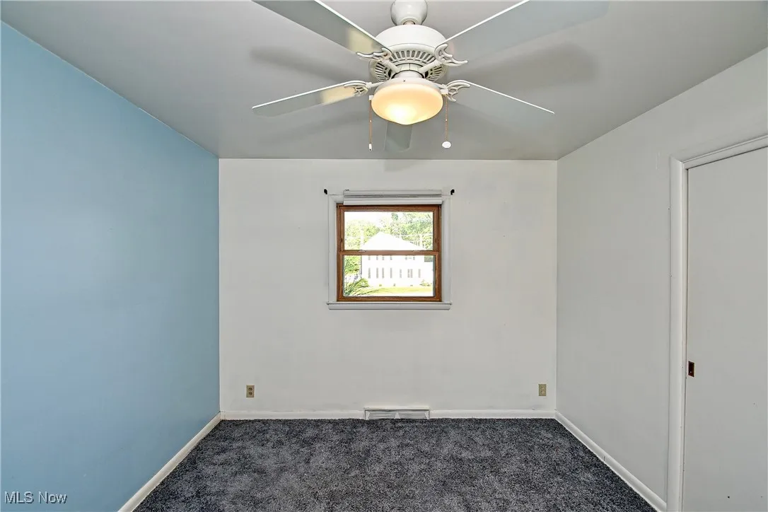Unfurnished room with dark carpet and baseboards