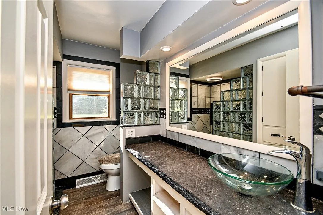 Bathroom featuring tile walls, dark wood-type flooring, vanity, and recessed lighting