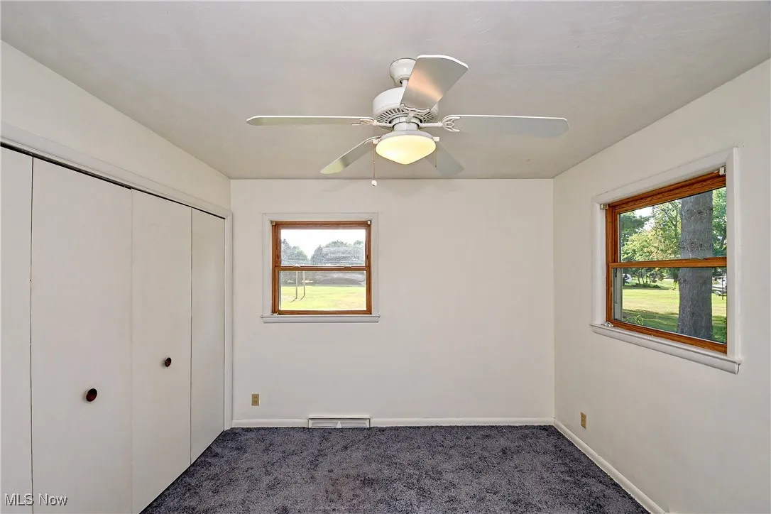 Unfurnished bedroom featuring dark carpet, a closet, and ceiling fan