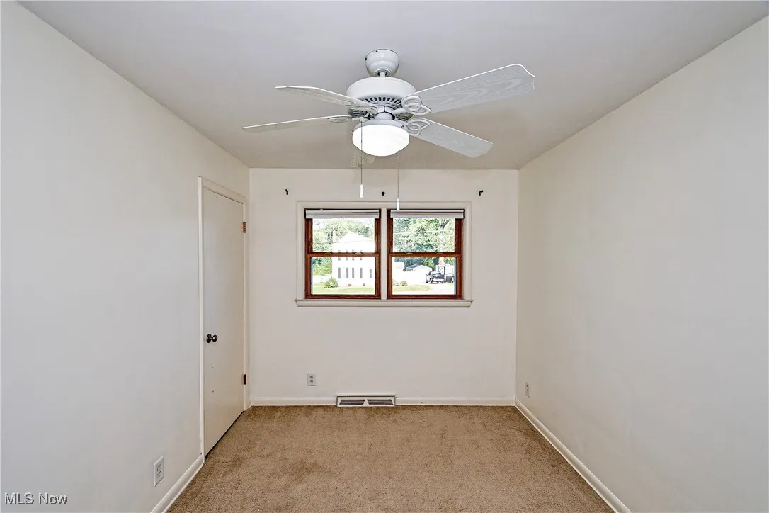 Empty room with light carpet and a ceiling fan