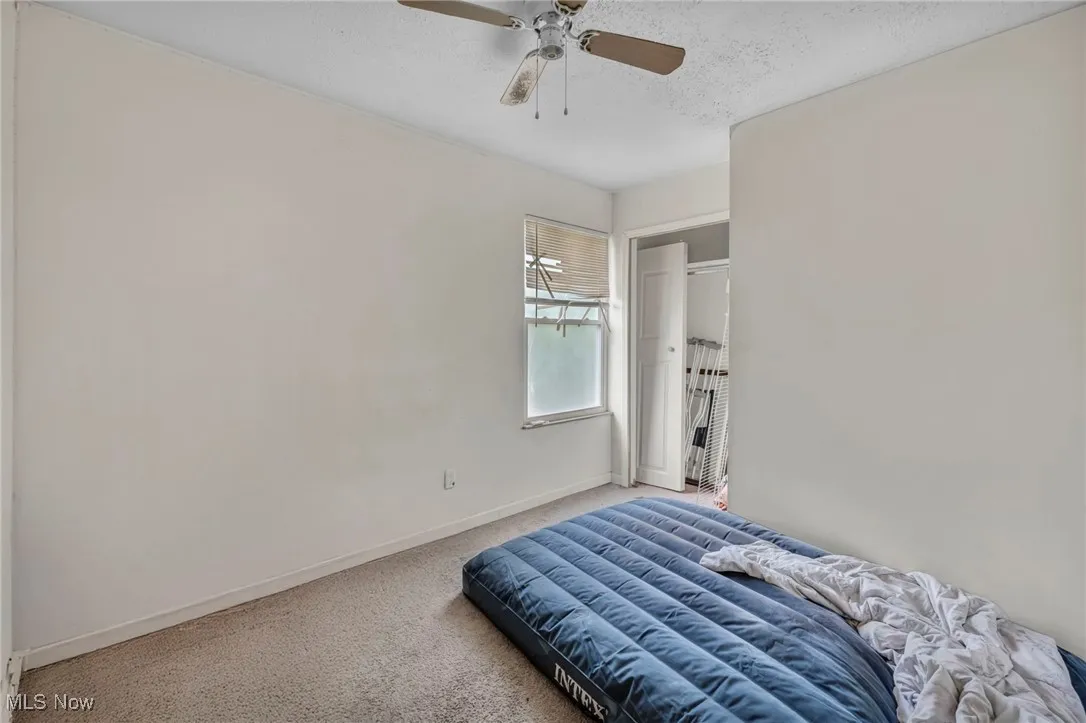 Carpeted bedroom with ceiling fan and a textured ceiling