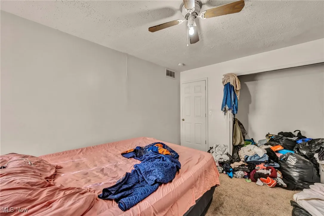 Bedroom featuring a textured ceiling, carpet flooring, and a ceiling fan