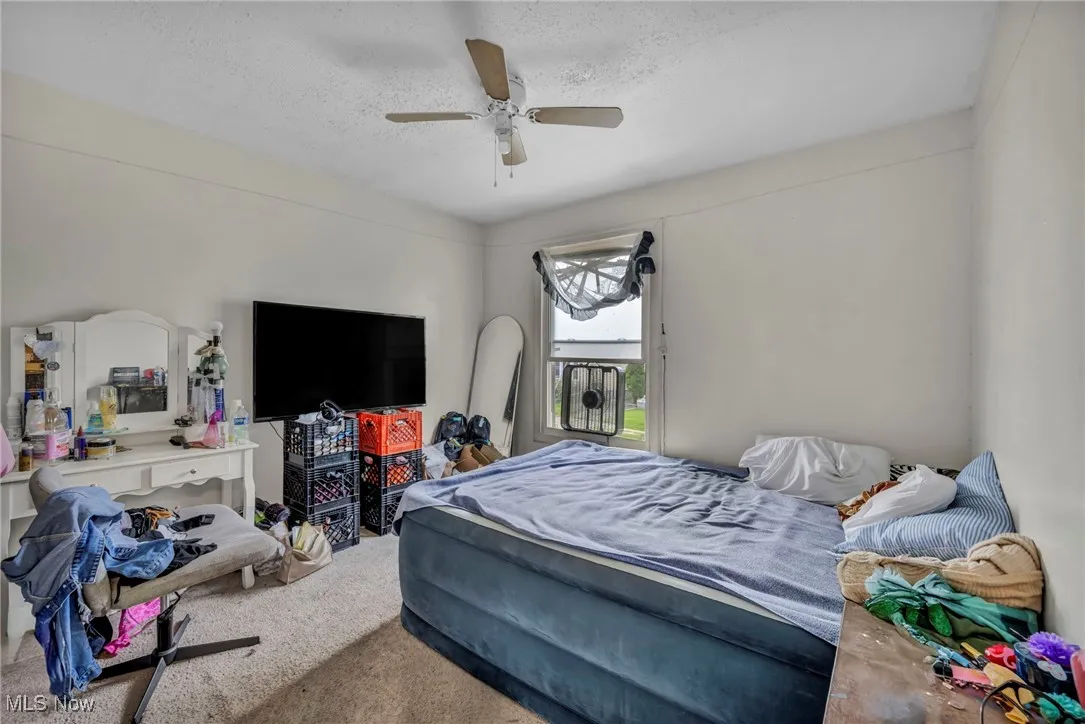 Bedroom featuring a textured ceiling, carpet floors, and ceiling fan