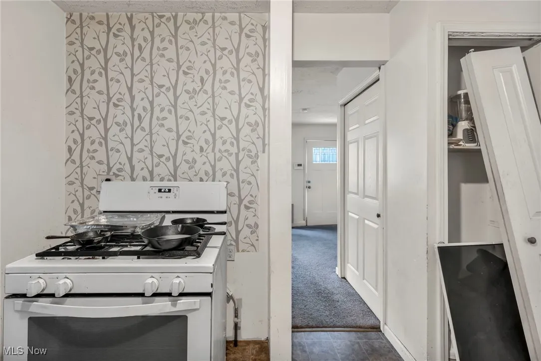 Kitchen featuring white gas stove and dark carpet
